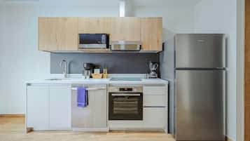 Uma cozinha moderna com armários brancos, uma geladeira de aço inoxidável, micro-ondas, forno Bosch e lava-louças.