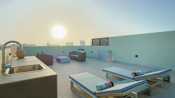 Um terraço no terraço com design moderno, incluindo uma pia, cadeiras de descanso e vista para o horizonte da cidade.