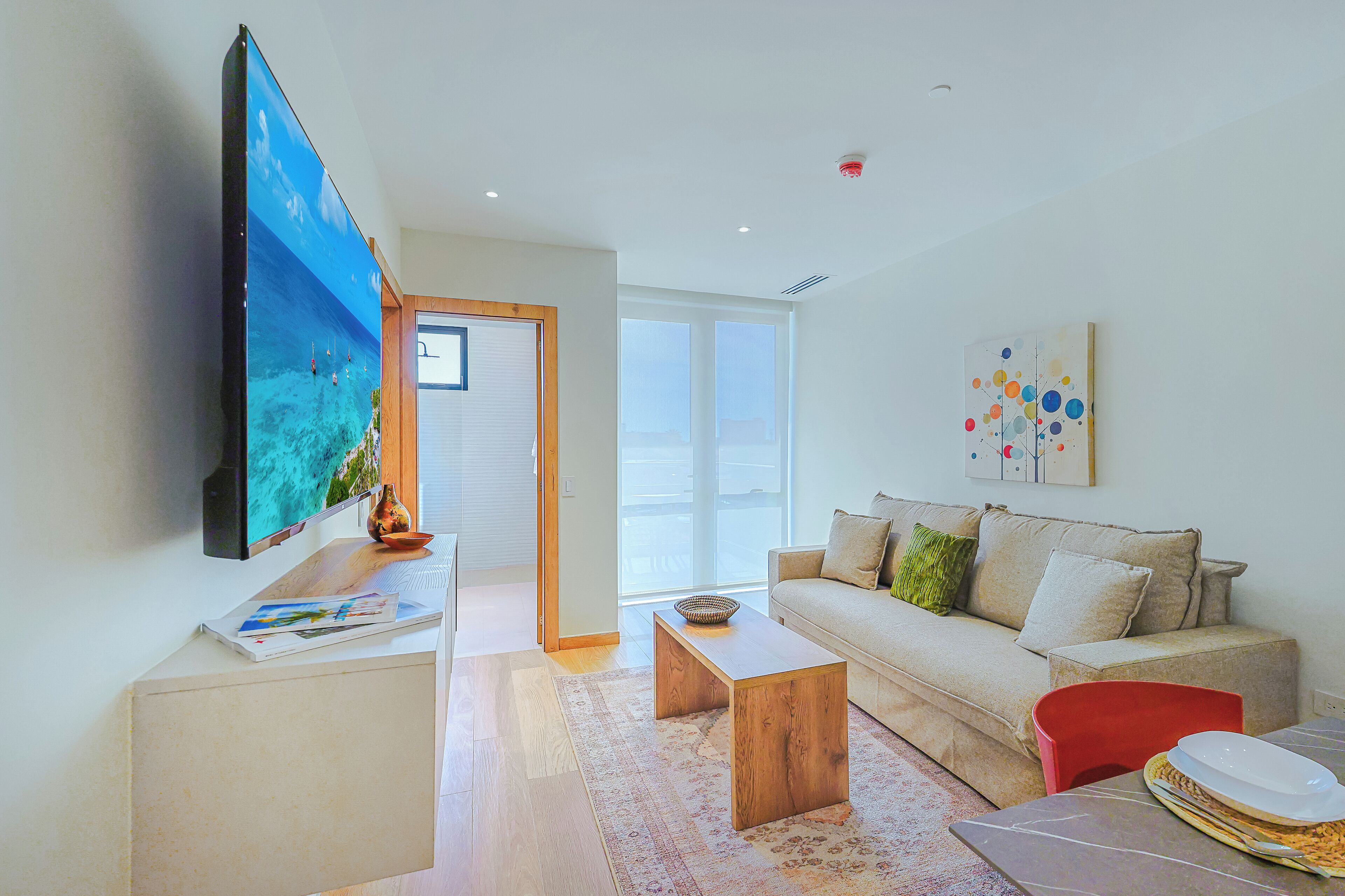 Uma sala de estar moderna com uma televisão de tela plana, um sofá, uma mesa de centro e uma mesa de jantar com cadeiras.