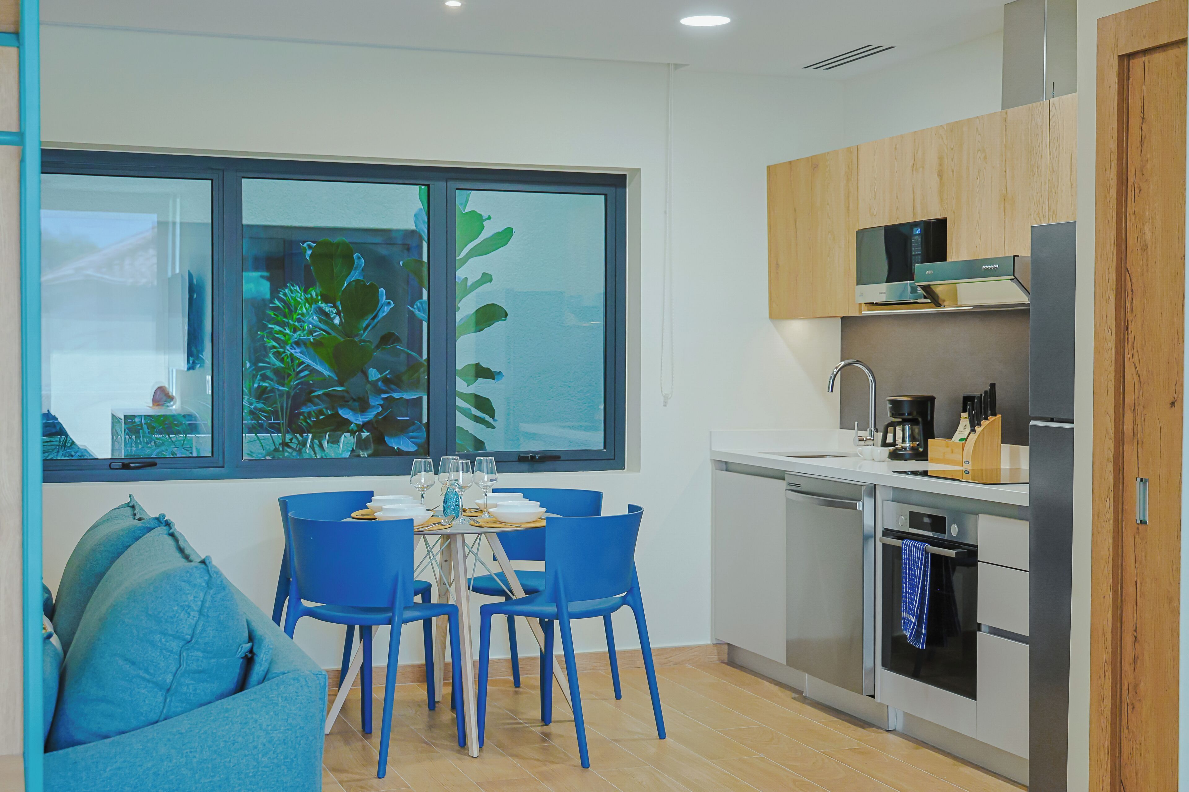 A modern kitchen with a dining area, featuring a large window, wooden cabinets, and a built-in microwave.