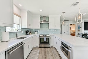 Cocina moderna con armarios blancos, electrodomésticos de acero inoxidable y una isla grande.