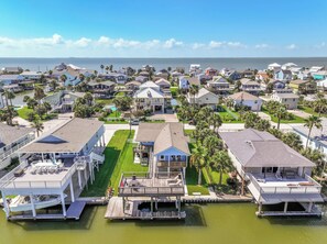 A coastal residential area with houses, a dock, and a clear view of the ocean. - Blue Haven | Canal-front retreat | Boat-Slip (Galveston)