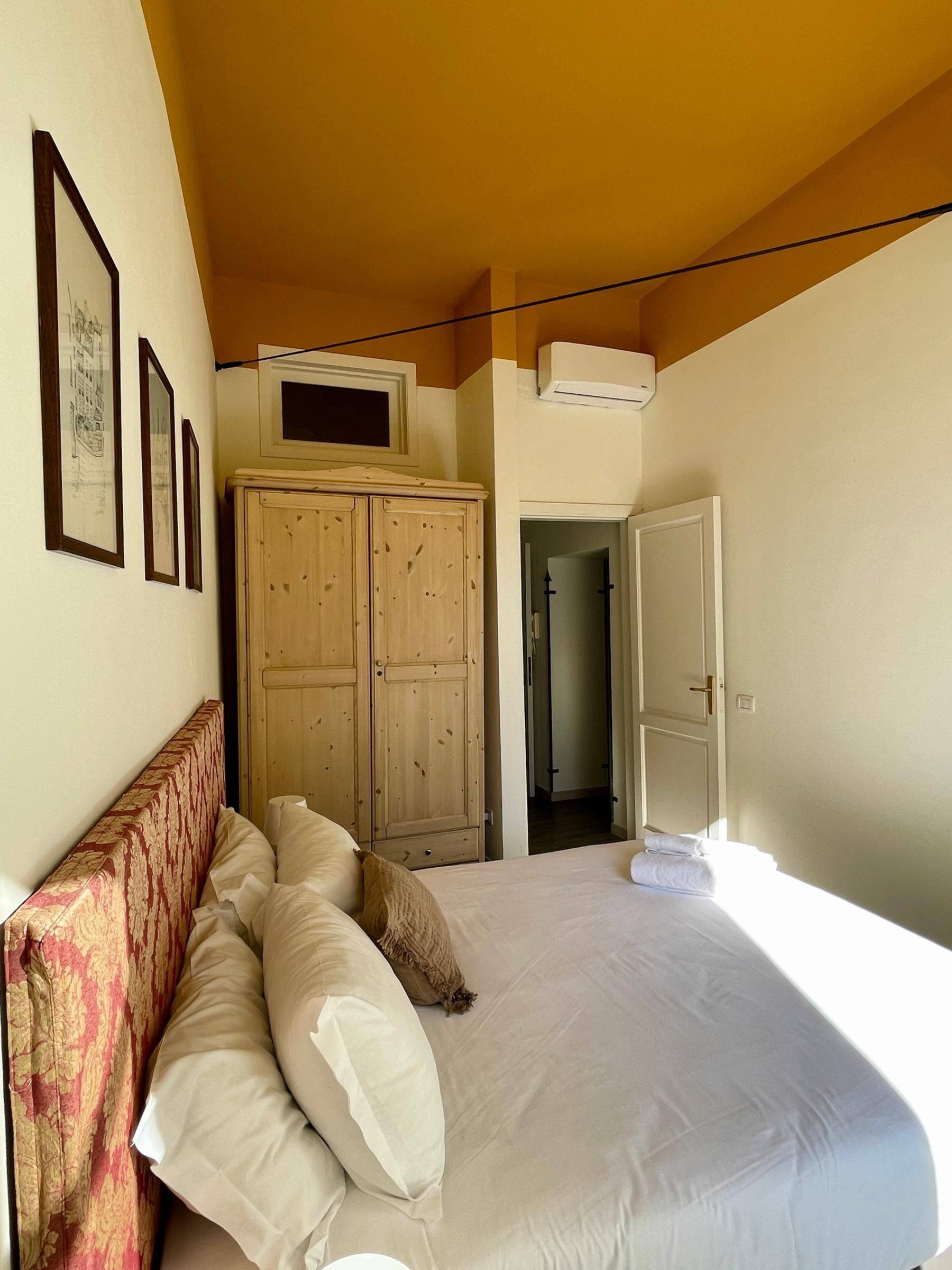 Une chambre à coucher comprenant un lit, une armoire et une porte donnant sur une autre pièce.