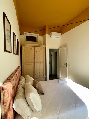 Une chambre à coucher comprenant un lit, une armoire et une porte donnant sur une autre pièce.