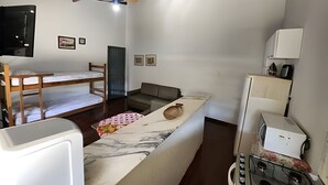 A compact room with a bunk bed, a sofa, a small table, and a kitchenette area. - DOURADOS GUEST FLAT (Dourados)