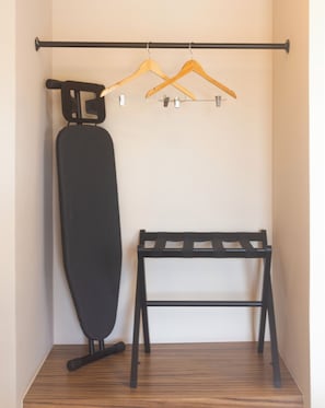A room with a black ironing board, a wooden hanger rack, and a black chair. - Hotel Moca (Cancún)