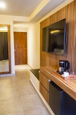 A modern kitchen with a built-in refrigerator, a coffee maker, and a flat-screen TV mounted on the wall. - Hotel Moca (Cancún)