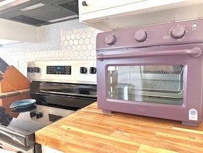 Una cucina con un forno viola, un microonde e un piano cottura in acciaio inossidabile.