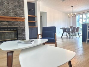 A modern interior with a fireplace, a dining area with chairs, and a table with a book.