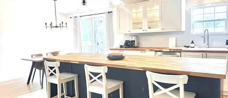 A kitchen with a central island, bar stools, pendant lighting, and a window providing natural light.
