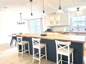 A kitchen with a central island, bar stools, pendant lighting, and a window providing natural light. - The Blue Pony - 5 Miles to WEC! 10 Miles to HITS! (Ocala)