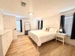 A bedroom with a bed, bedside table, lamp, wardrobe, and a window with curtains. - The Blue Pony - 5 Miles to WEC! 10 Miles to HITS! (Ocala)