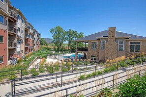 A residential complex with multiple apartment buildings, a swimming pool, and a landscaped area with pathways and seating. - 1-bed by Jordan Creek & Top Golf (West Des Moines)