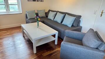 Ein Wohnzimmer mit weißem Couchtisch, grauem Sofa und grauem Sessel.