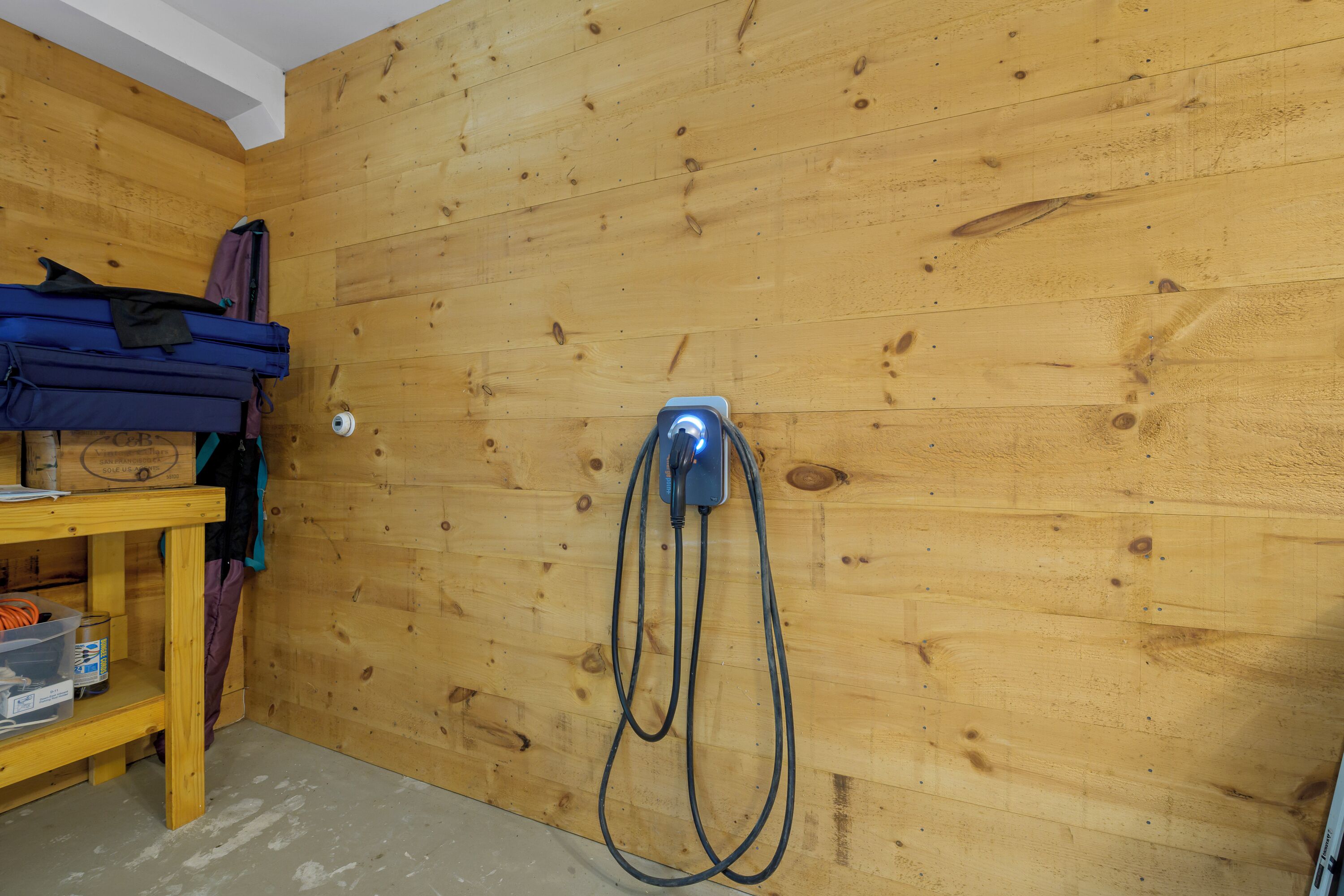Een kamer met een houten wand, een stopcontact en een tafel met spullen erop.