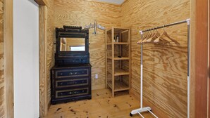 Ein kleiner Raum mit Holzwandverkleidung, einem Schminktisch, einem Spiegel und einem Kleiderständer.