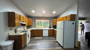 Una cucina con mobili in legno, un frigorifero bianco e una finestra vista verde.