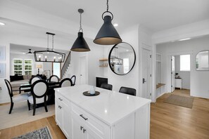 A modern kitchen with a white island, black pendant lights, and a large mirror above the island. - East Nash Luxe Minutes to Nissan Stadium & Five Points (Nashville)