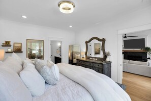 Une chambre moderne avec un grand lit, une commode, un téléviseur et une cheminée.