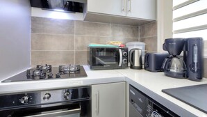 A modern kitchen with a gas stove, microwave, kettle, and coffee maker. - Le Mosala 1 - Climatisation - Vue mer (Saint-Leu)