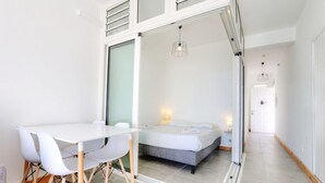 A modern hotel room with a bed, a dining table with chairs, and a large window. - Le Mosala 1 - Climatisation - Vue mer (Saint-Leu)