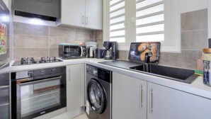 A modern kitchen with a built-in oven, microwave, coffee maker, and a washing machine. - Le Mosala 1 - Climatisation - Vue mer (Saint-Leu)
