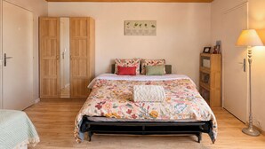 A bedroom with a bed, a nightstand, a lamp, and a wardrobe. - La Madeleine - Balcon - Quartier Château (Bagnoles de l'Orne Normandie)