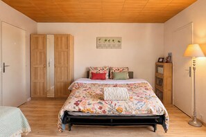 A bedroom with a bed, a nightstand, a lamp, and a wardrobe. - La Madeleine - Balcon - Quartier Château (Bagnoles de l'Orne Normandie)