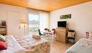 Habitación de hotel con cama, escritorio, silla, televisor y vista al exterior.
