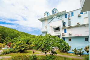 A multi-story hotel with a light blue facade, a balcony, and a sign that reads 'Régina'. - Le Nid bleu -Climatisation -Proche plage (SAINTE ANNE)