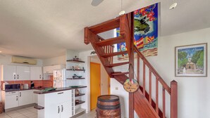 A kitchen with white cabinets, a microwave, and a wooden barrel. - Melody - Climatisation - Proche plage (SAINTE ANNE)