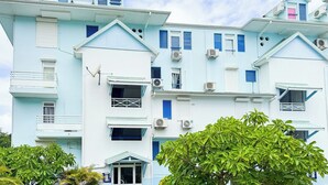 A multi-story building with balconies, air conditioning units, and a satellite dish. - Melody - Climatisation - Proche plage (SAINTE ANNE)
