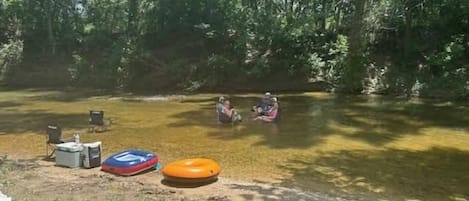 Un campamento con una tienda de campaña, una hielera y un flotador inflable en el suelo.