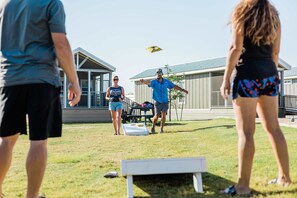 En grupp människor som spelar frisbee på en gräsyta med en byggnad i bakgrunden.