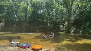 Un campeggio con una tenda, un borsone frigo e un cerchio gonfiabile a terra.