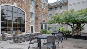 An outdoor patio with seating, a fire feature, and a tree.