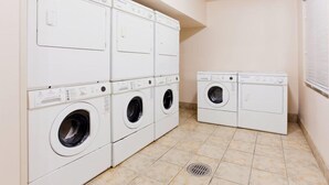 A laundry room with multiple stacked washing machines and dryers.