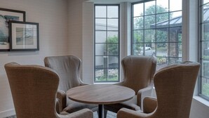 A room with a round table and four chairs, large windows with a view of greenery, and framed artwork on the wall. - Accessible 1BR King Suite | Free Breakfast + Pool (Allentown)