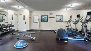 A gym with exercise equipment, a bench, and dumbbells.