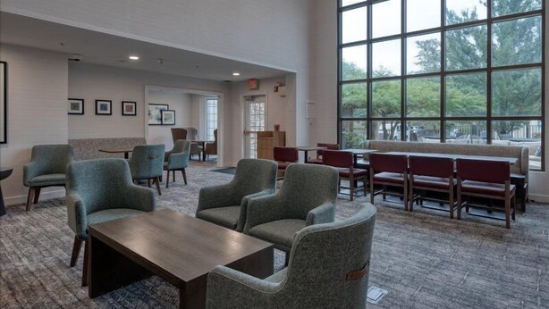 A spacious indoor area with multiple seating arrangements, including chairs and benches, and large windows providing natural light. - Accessible 1BR King Suite | Free Breakfast + Pool (Allentown)