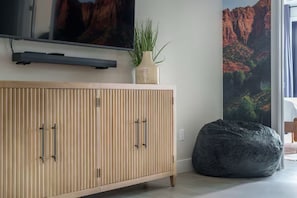 Ein modernes Wohnzimmer mit einem Holzkabinett, einem Flachbildfernseher, einer Topfpflanze und einem Sitzsack.