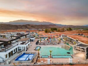 Ein Resort mit mehreren Schwimmbecken, Außenbereichen zum Sitzen und einer Bergkulisse.