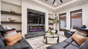A modern living room with a fireplace, leather sofas, and built-in shelves. - Zion Vacation - Sleeps 12 - Hot Tub, Golf, Waterpark (Hurricane)