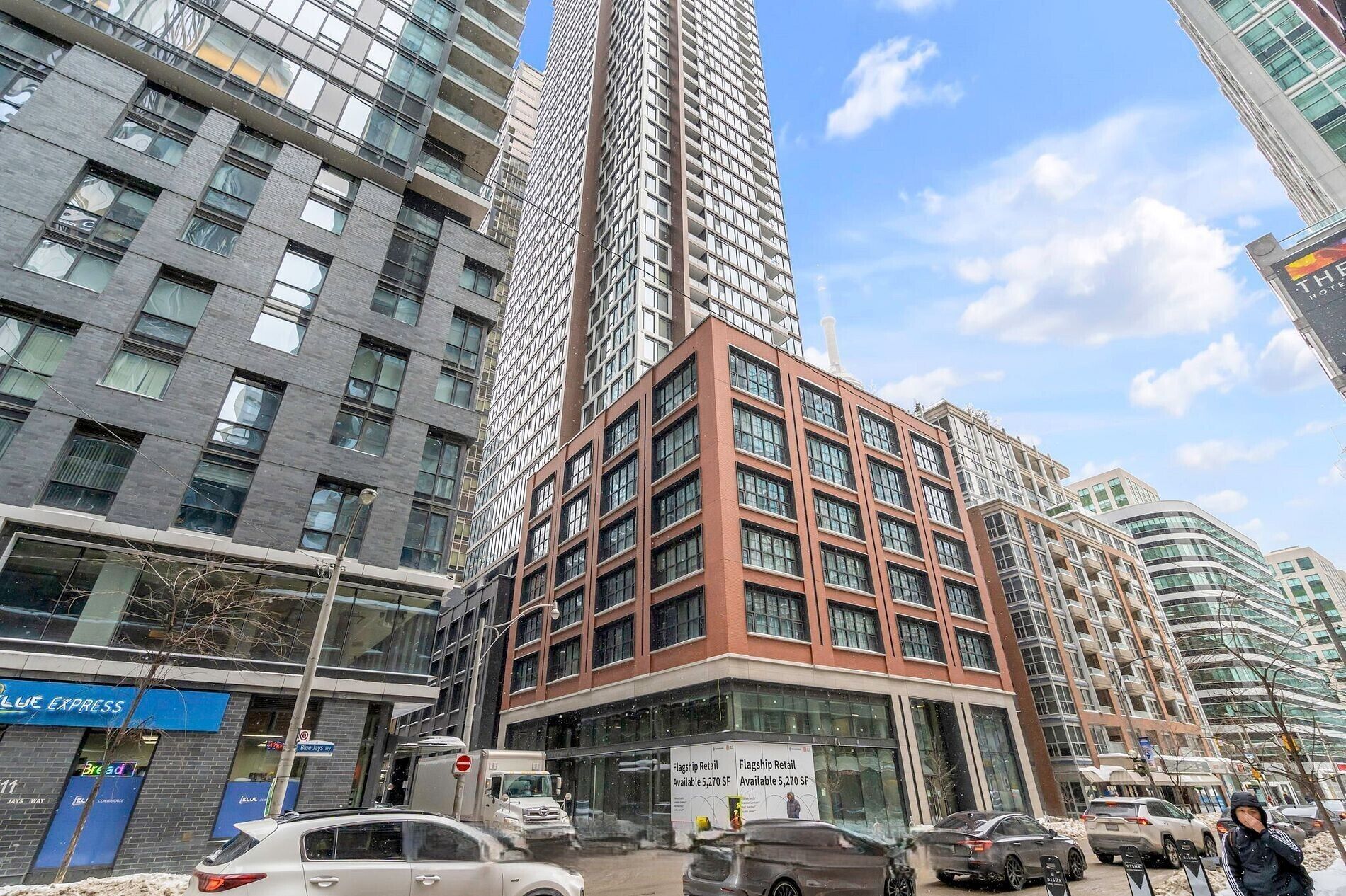 A multi-story building with a mix of glass and brick facades, surrounded by other high-rise buildings.