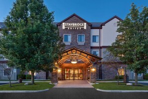 Der Eingang eines Staybridge Suites Hotels mit Ziegel Fassade, großen Fenstern und einem einladenden Bogen.