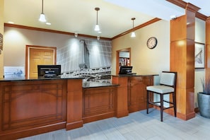 A kitchen with wooden cabinetry, a built-in island, pendant lighting, a clock on the wall, and a potted plant. - Accessible 2BR Suite w/ Tub | Breakfast + Pool (Kalamazoo)