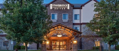 A Staybridge Suites hotel entrance with a brick facade, large windows, and a welcoming archway.