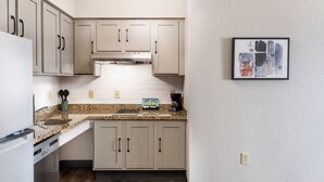 Uma cozinha moderna com bancadas de granito, eletrodomésticos de aço inoxidável e armários de cor clara.