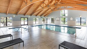 A large indoor swimming pool with a high wooden ceiling and multiple windows.