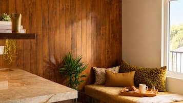 A cozy room with a wooden wall, a cushioned bench, a marble countertop, and a hanging light fixture.